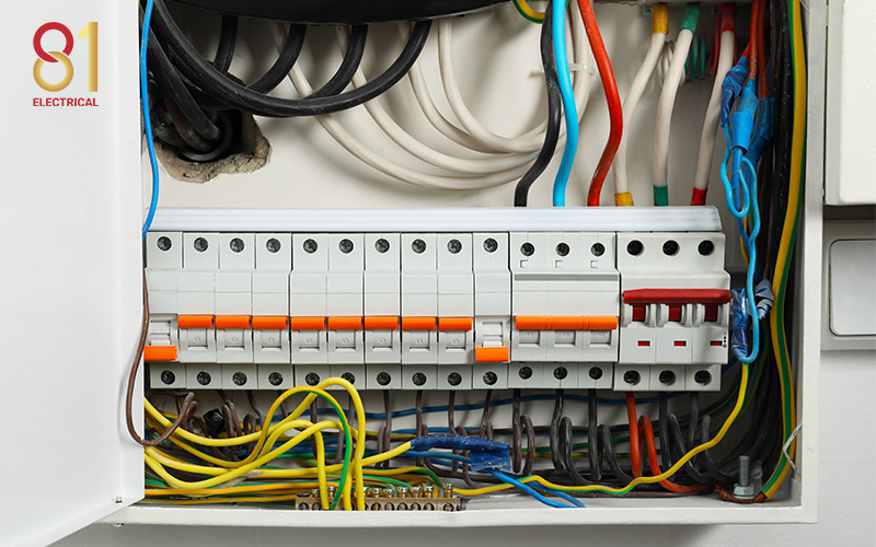 Electrical panelboard with wires and circuit breakers.