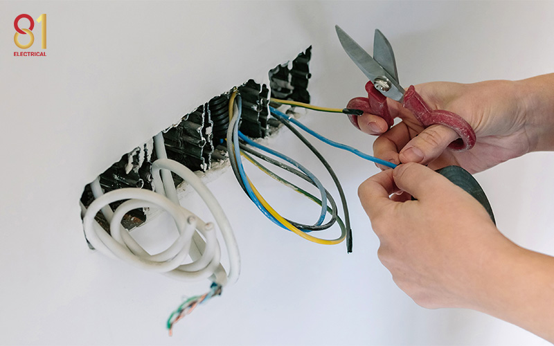 Electrician cutting wires for electrical rewiring in Singapore.