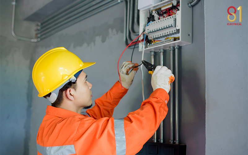 Electrician installing wiring in an electrical control panel.