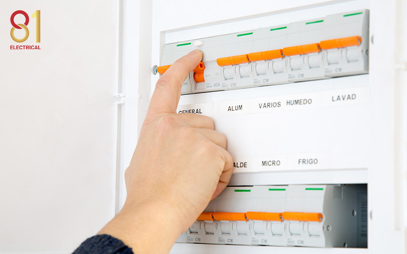 Hand flipping a circuit breaker on a panelboard