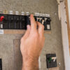 Hand resetting an old circuit breaker switch.