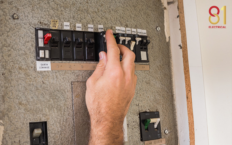 Hand resetting an old circuit breaker switch.
