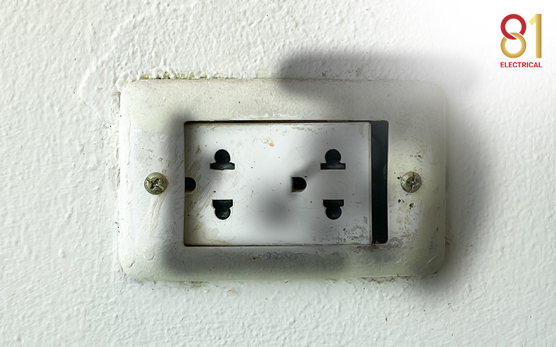 Dirty electrical outlet on a white wall with two screws.