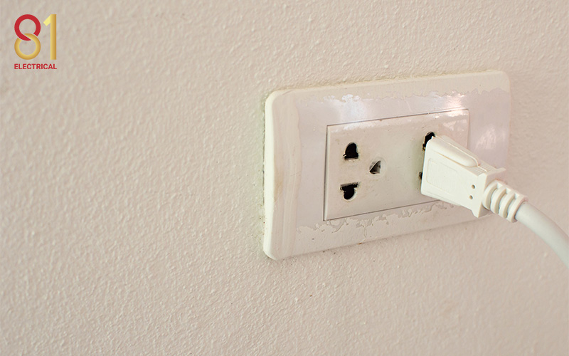 White electrical plug partially pulled out of a wall outlet.
