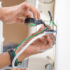 Electrician taping exposed electrical wires.
