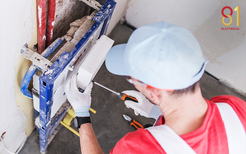 Electrician installing an electrical box in wall.