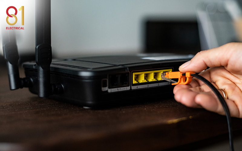 A person plugging an ethernet cable into a router.
