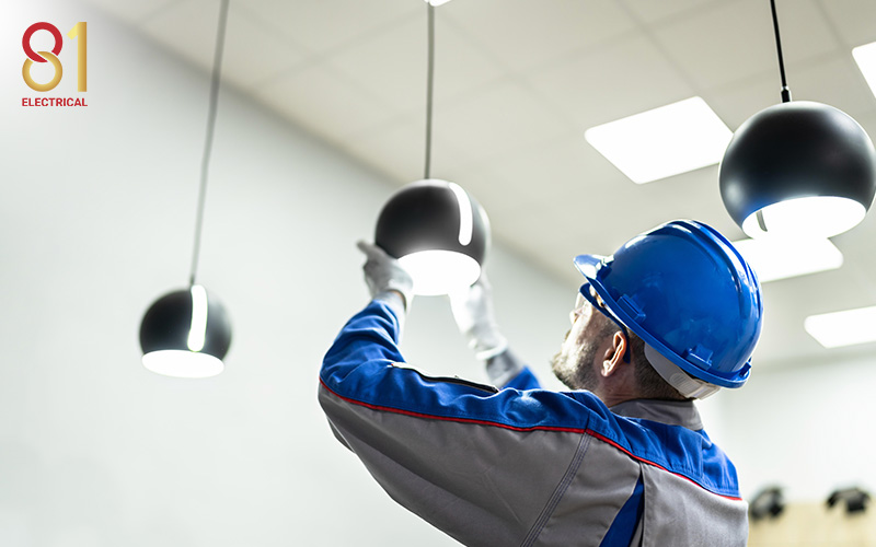 Electrician installing a new light fixture in an office.