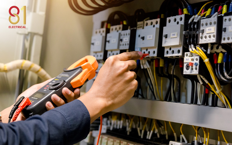 Electrician measuring voltage in an electrical box.