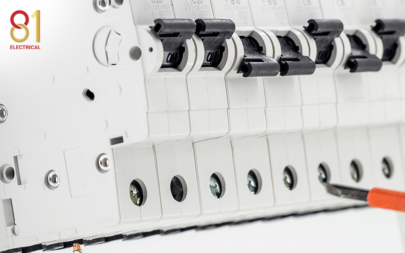 Electrician's screwdriver tightening a screw on a circuit breaker.