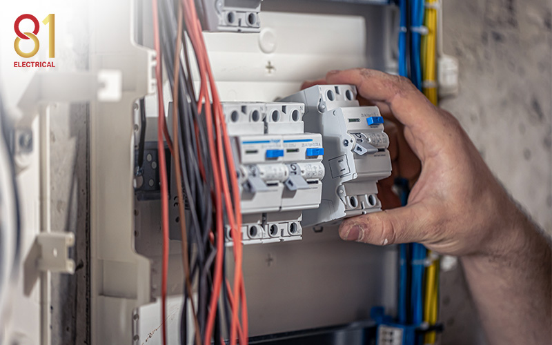 Hand installing an electrical circuit breaker in a fuse box.