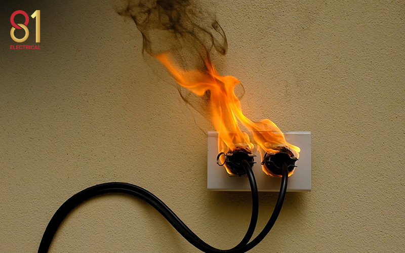 Wall socket with an overloaded plug on fire.