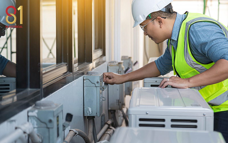 Electrician inspecting an AC unit for electrical circuits.