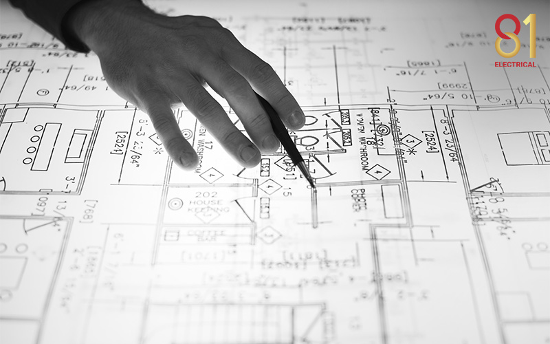 Hand pointing to a blueprint for proper circuit planning.